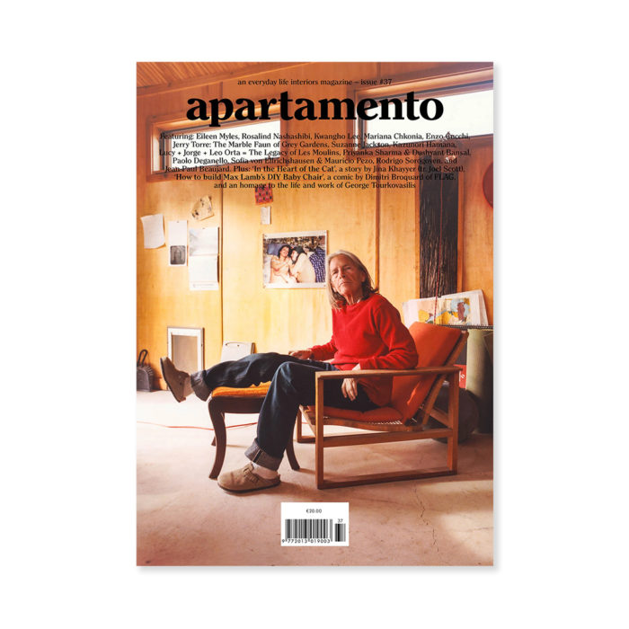 Magazine cover titled 'apartamento' featuring an older man seated in an orange chair in a warm, cluttered studio with photos on the wooden wall and a barcode at the bottom.